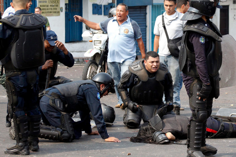 Un agente yace en el suelo tras ser atropellado por un autobús durante una  protesta en San Cristobal. (FOTO: Carlos Eduardo Ramírez/Reuters)