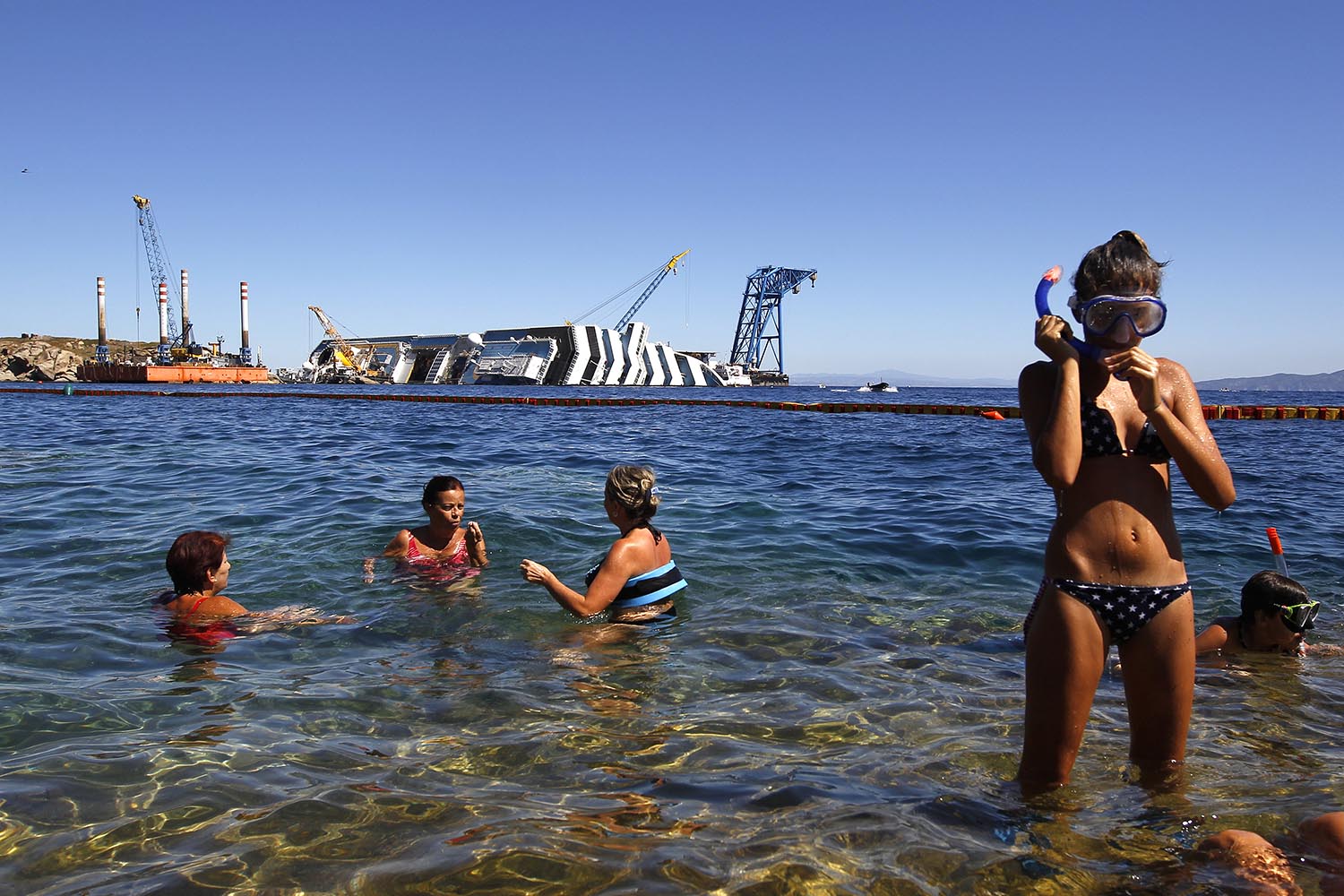 Especial Un mundo pequeño. Unos turistas se bañan en la zona del naufragio del Costa Concordia