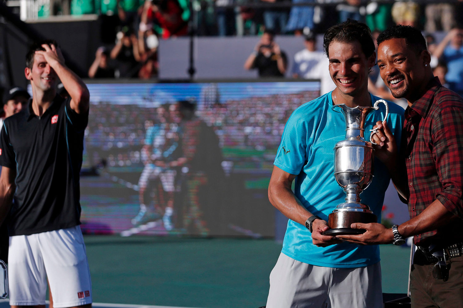 Rafa Nadal recibe un trofeo de manos del actor Will Smith tras ganar a Djokovic.