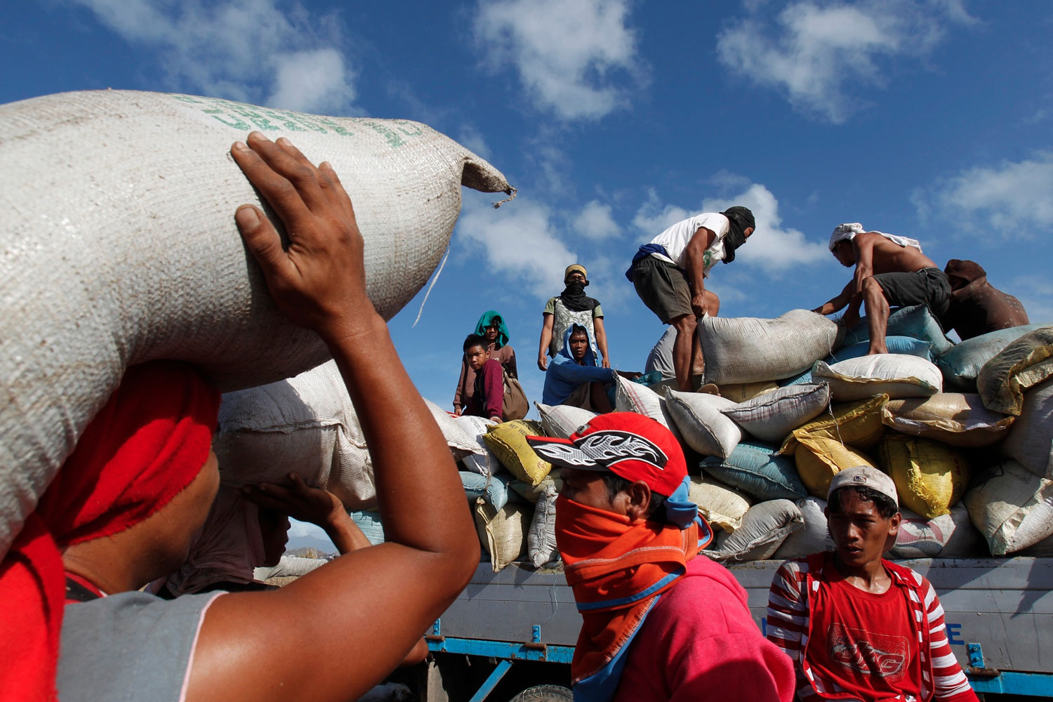varios filipinos recogen sacos de arroz de una fábrica derruida en Tacloban