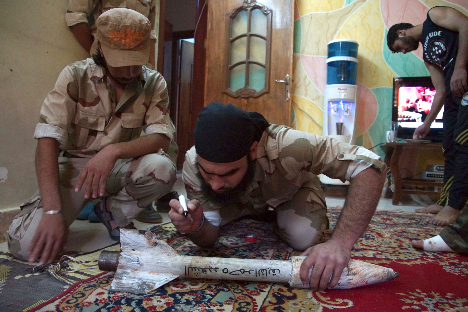 Un miembro del Ejército Libre de Siria, escribe el nombre de un compañero de combate en un cohete.