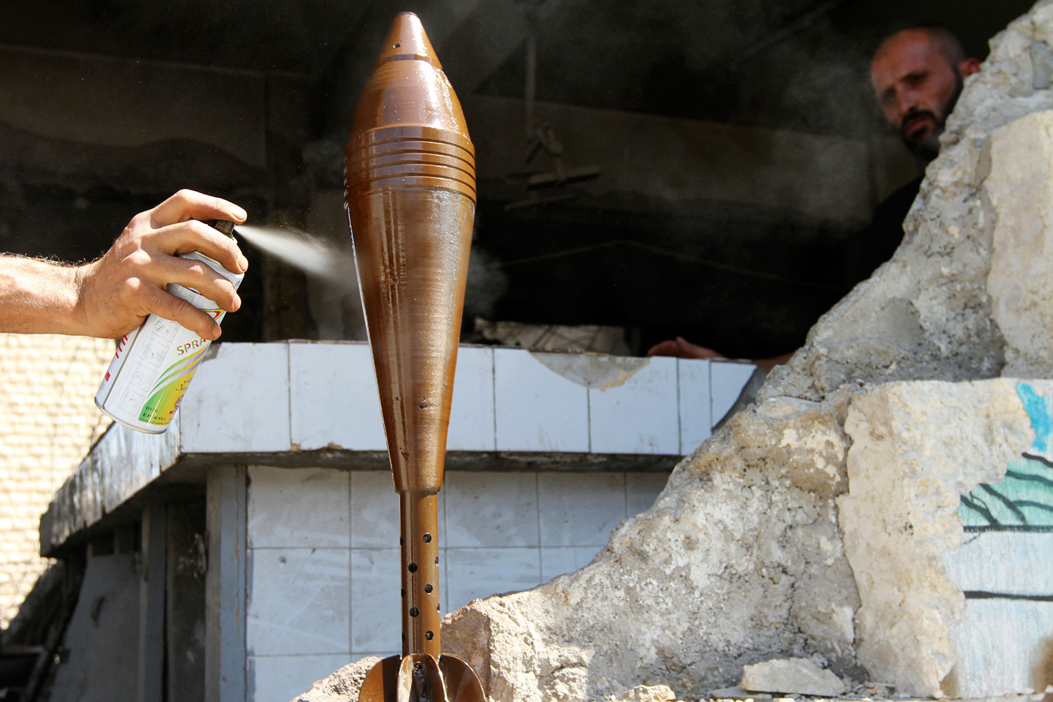 Un combatiente pinta con aerosol un proyectil de mortero improvisado en Aleppo.