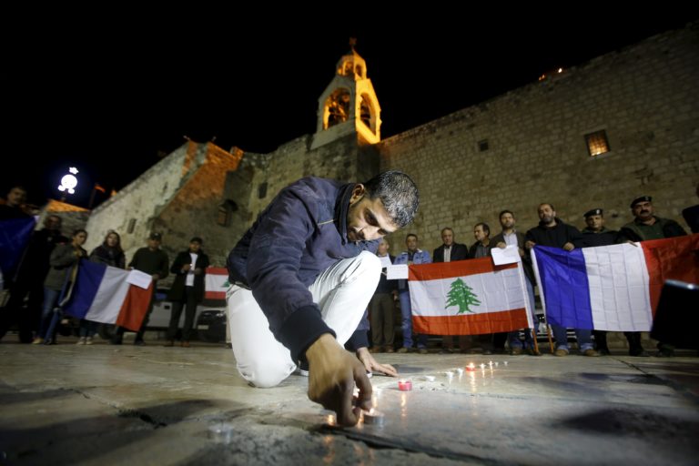 Un palestino enciende una vela durante una manifestación en solidaridad con las víctimas de los ataques de París y el reciente bombardeo de Líbano en la ciudad cisjordana de Belén (REUTERS/Mussa Qawasma)
