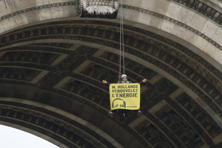 Un activista de Greenpeace cuelga de la parte superior del Arco de Triunfo con una pancarta que dice "Señor Hollande, renueve la energía" (REUTERS/Charles Platiau)