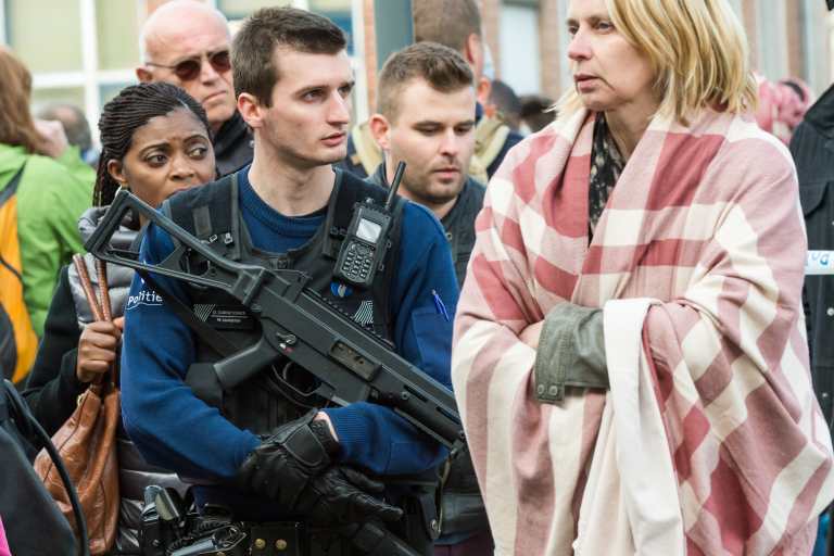 Un policía armado acompañado por varios evacuados del aeropuerto de Bruselas (AP Photo/Geert Vanden Wijngaert)