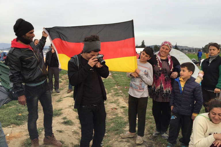 Un grupo de refugiados junto con la bandera de Alemania 