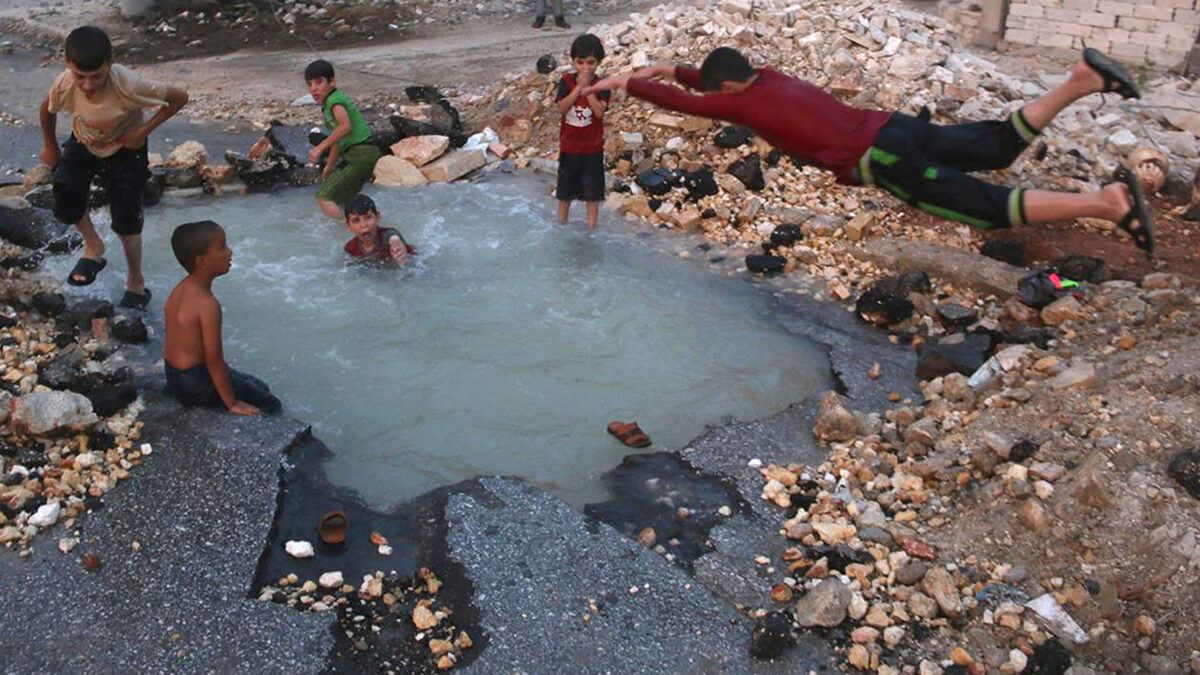 Niños sirios nadan en el cráter dejado por una bomba en Alepo