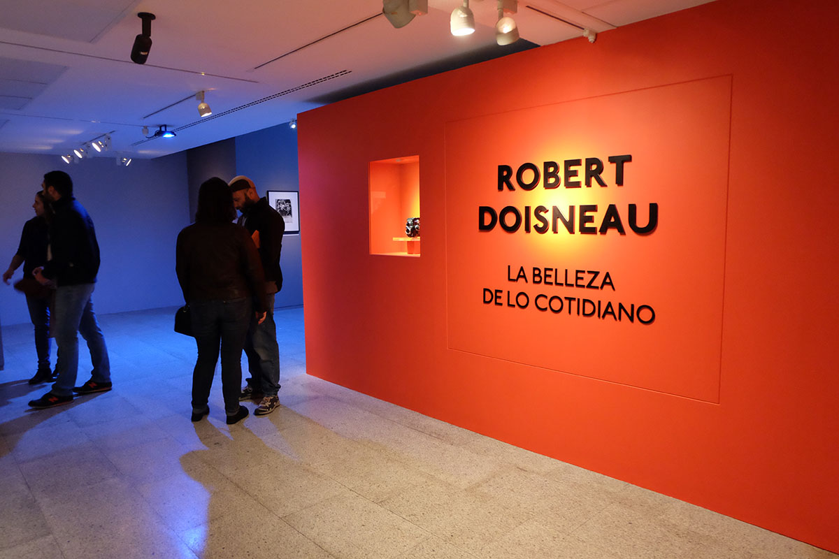 Varios visitantes entran en la exposición Robert Doisneau: la belleza de lo cotidiano en la Fundación Canal de Madrid. (Foto: Ana Laya / The Objective)