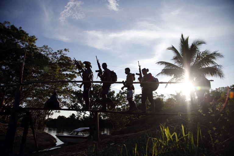 In this Aug. 12, 2016 photo, rebels of the 48th Front of the Revolutionary Armed Forces of Colombia walk on a makeshift footbridge in the southern jungles of Putumayo, Colombia. With the peace accords about to signed between the FARC and the governemt, gone are the days when they had to change camp every few days for fear of being stunned in their sleep by bombs falling from the skies.  (AP Photo/Fernando Vergara)