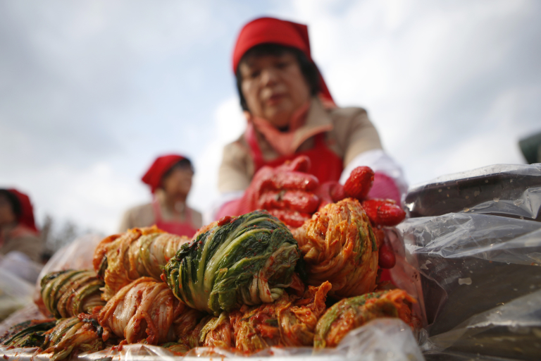 A woman makes traditional Korean side dish kimchi, or fermented cabbage, during the 2014 Seoul Kimchi Making and Sharing Festival at Seoul City Hall Plaza in Seoul November 14, 2014. More than 2,300 volunteers made 250 tonnes of kimchi on Friday to give away to needy people during the winter season.   REUTERS/Kim Hong-Ji (SOUTH KOREA - Tags: FOOD SOCIETY) - RTR4E3RR