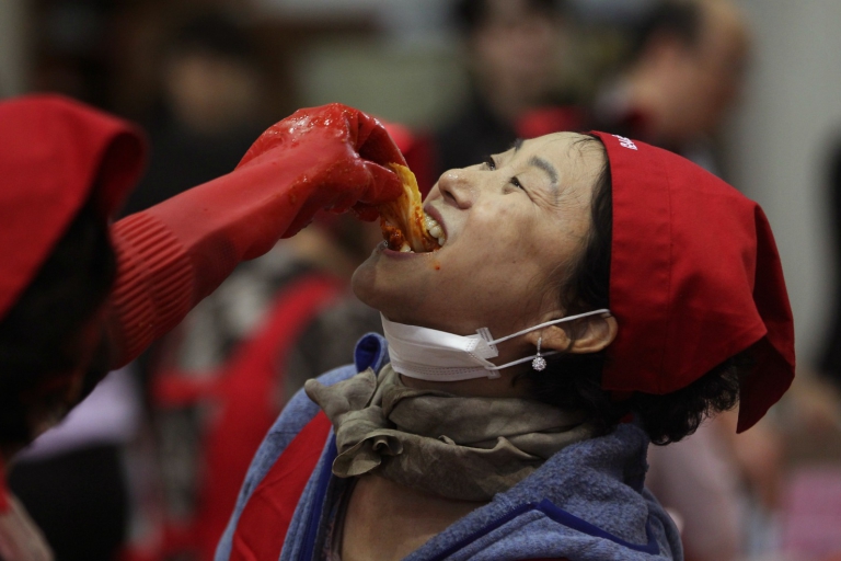 An unidentified woman tastes of kimchi, traditional pungent vegetable, to donate to needy neighbors for winter preparation at a government building in Seoul, South Korea, Wednesday, Oct. 28, 2015. About 100 volunteers made 5,500kg of kimchi. Made with cabbage, other vegetables and chili sauce, kimchi is the most popular traditional food in Korea.(AP Photo/Ahn Young-joon)