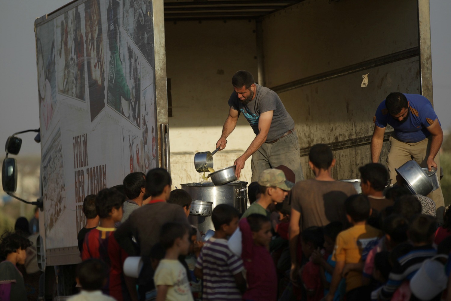 Un grupo de desplazados sirios recibe comida de organizaciones civiles del país. (Foto: Khalil Ashawi / Reuters) 