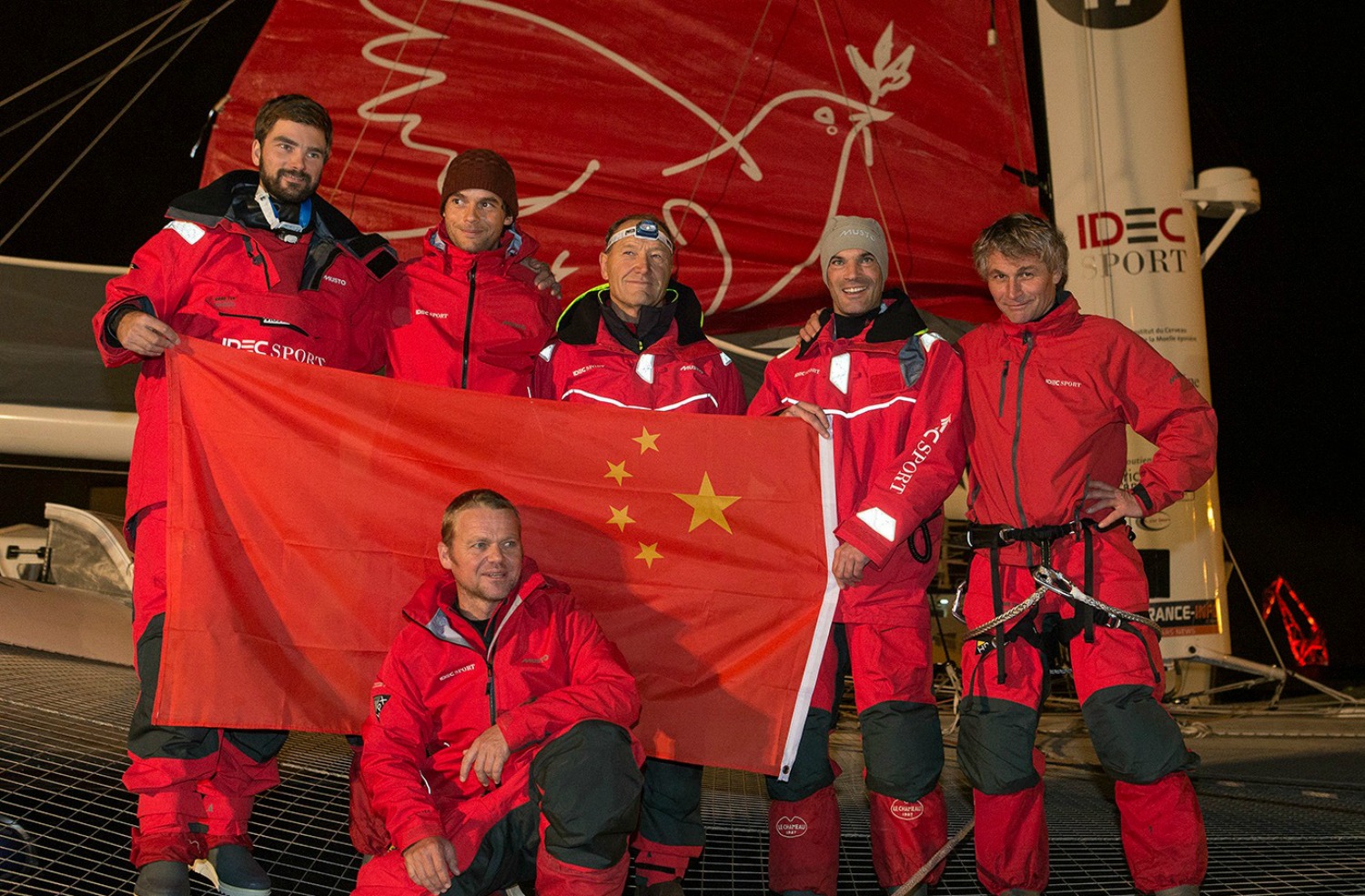 La tripulación del IDEC Sport en Brest, minutos antes de zarpar, rindiendo homenaje al navegante chino Guo Chuan, recientemente desaparecido mientras intentaba el Record entre San Francisco y Pekín.