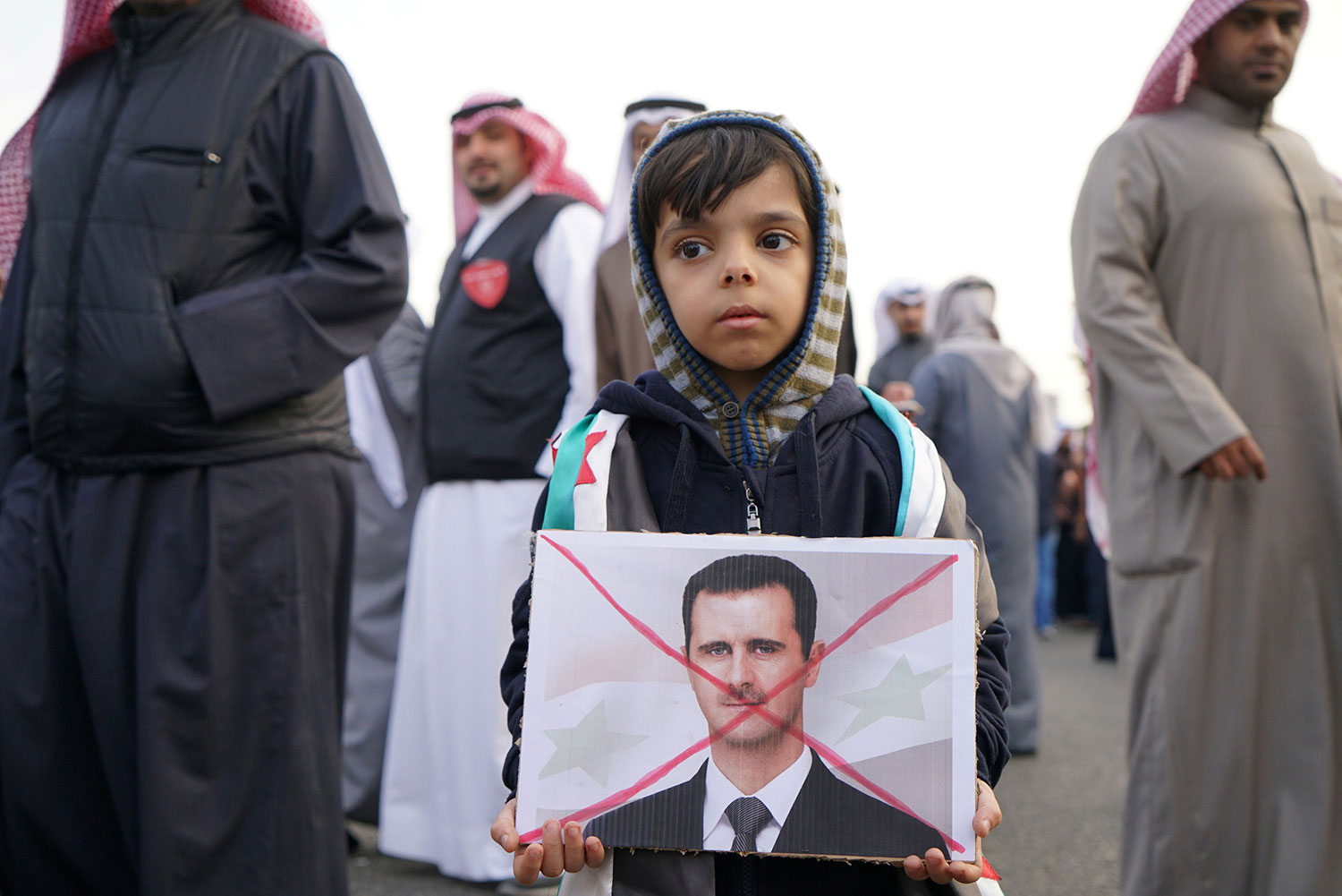 Un niño sostiene un signo contra el presidente Al-Assad en una protesta frente a la Embajada de Rusia el 14 de diciembre en  Shaab, Kuwait | Foto: Stephanie McGehee / Reuters.