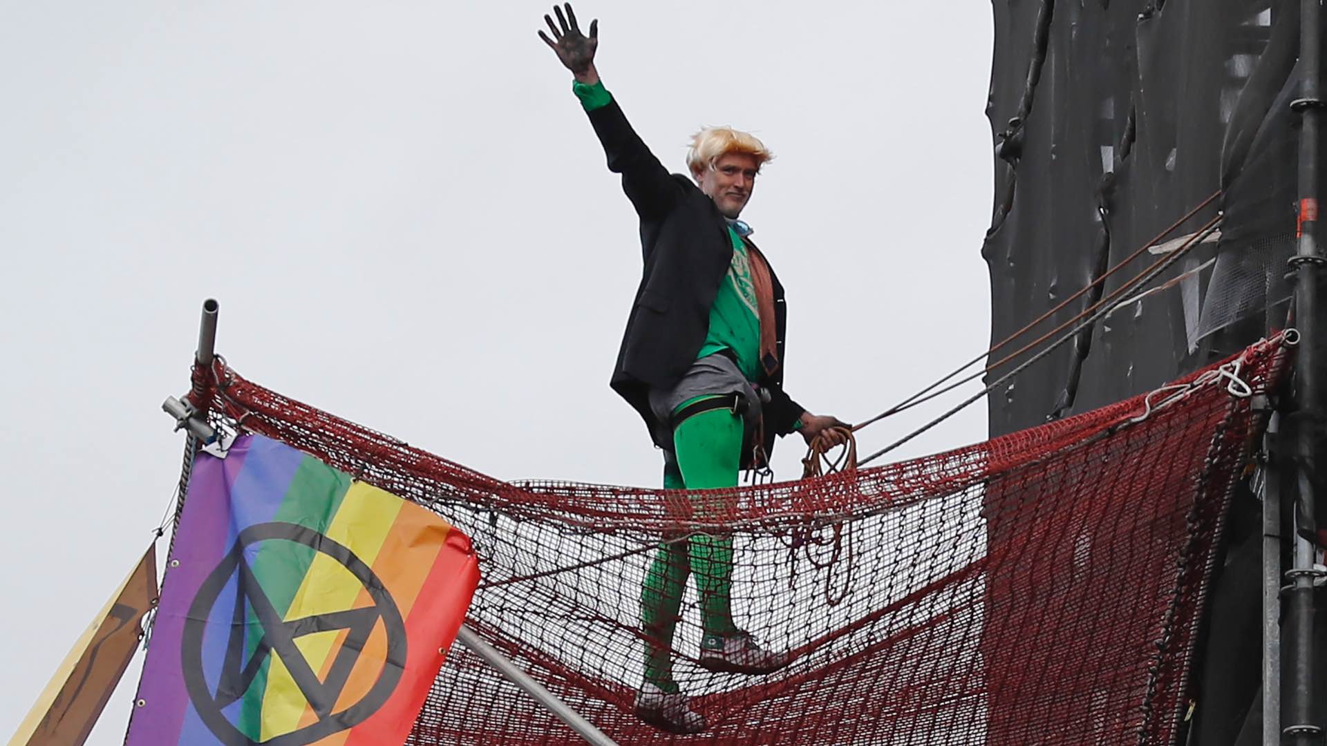 Un activista disfrazado de Boris Johnson cuelga dos banderas ecologistas en la torre del Big Ben