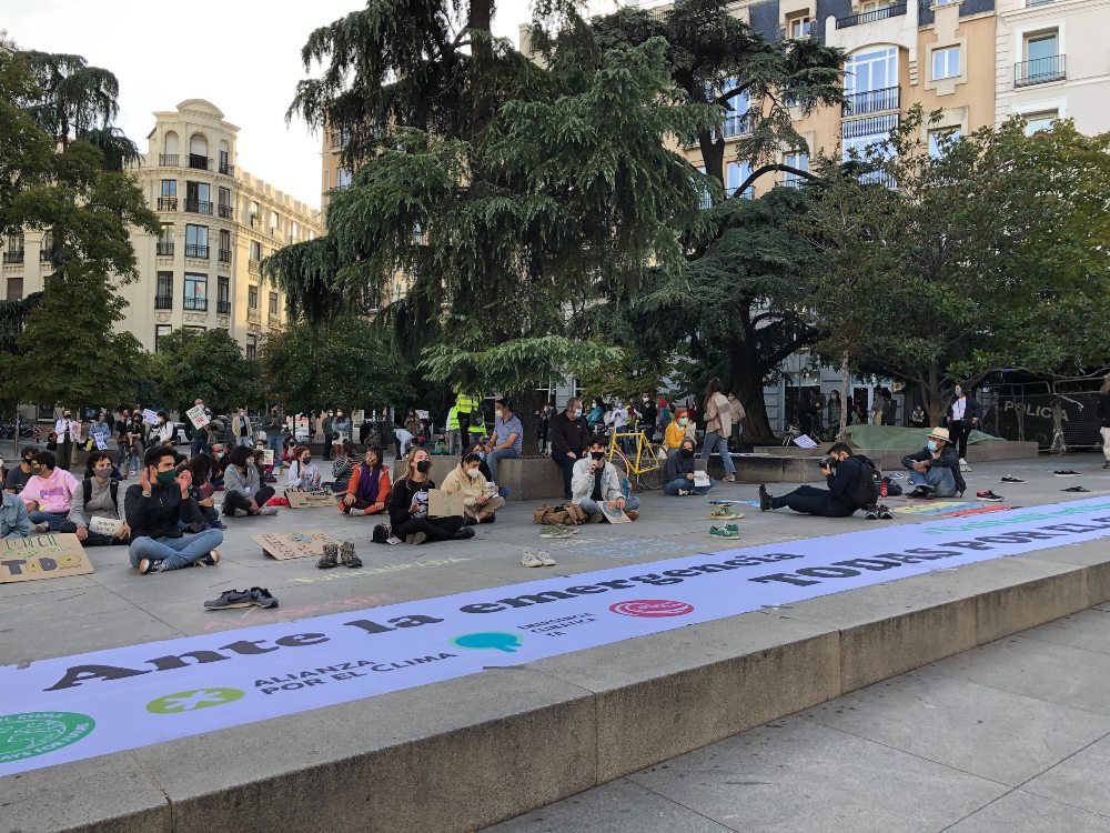 Activistas de Fridays For Future protestan sentados y con mascarilla ante el Congreso de los Diputados