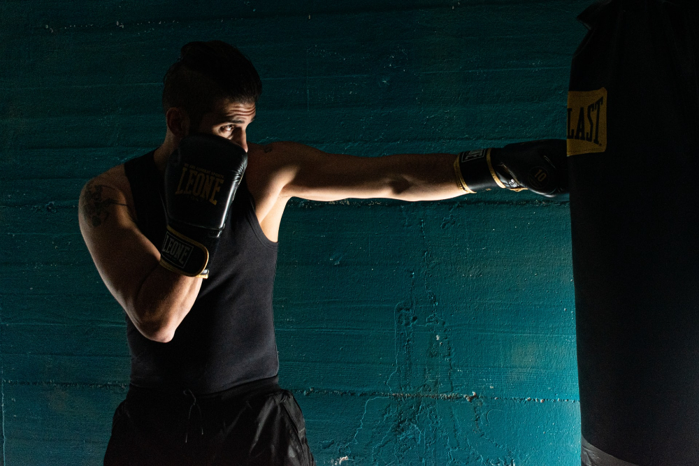 Fotografía oscura de niños entrenando con un gran saco de boxeo en
