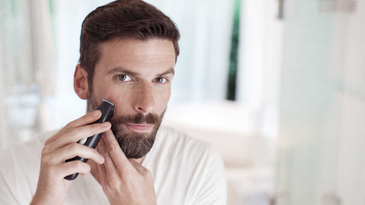 Hombre perfilando su barba con una maquinilla eléctrica (fuente: Homine Madrid)