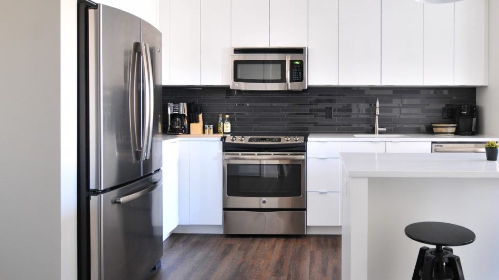 Cocina de color blanca y negra con electrodomésticos en color plateado