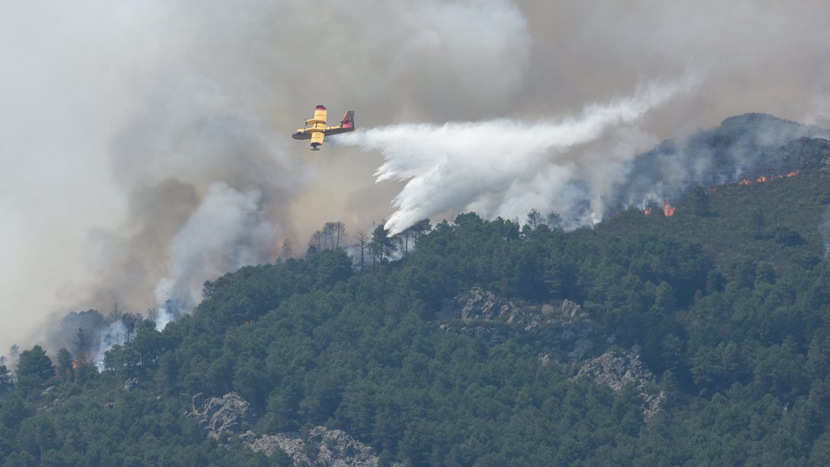 Un hidroavión anfibio contra incendios echa agua sobre la vegetación en la comarca de Las Hurdes, Extremadura