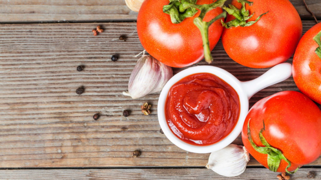 Un bol con salsa de tomate y varios tomates alrededor. 