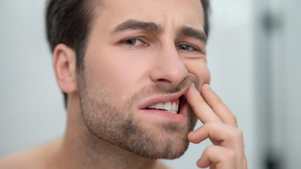 Un hombre se sujeta el labio por dolor de encías