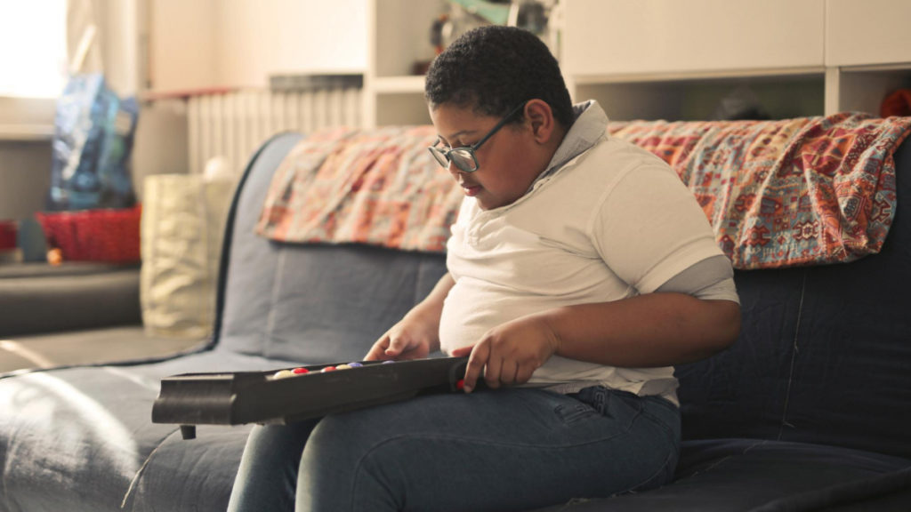 Un niño con sobrepeso juega al pinball en el sofá