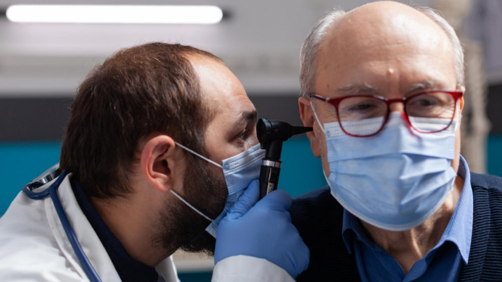 Un médico revisa el oído de un anciano con un otoscopio para ver si debe dejar de conducir