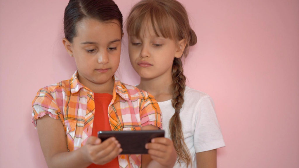 Dos niñas ven un vídeo en un teléfono móvil
