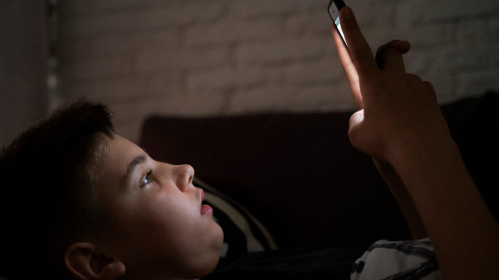 Un niño tumbado ve un vídeo en un teléfono móvil