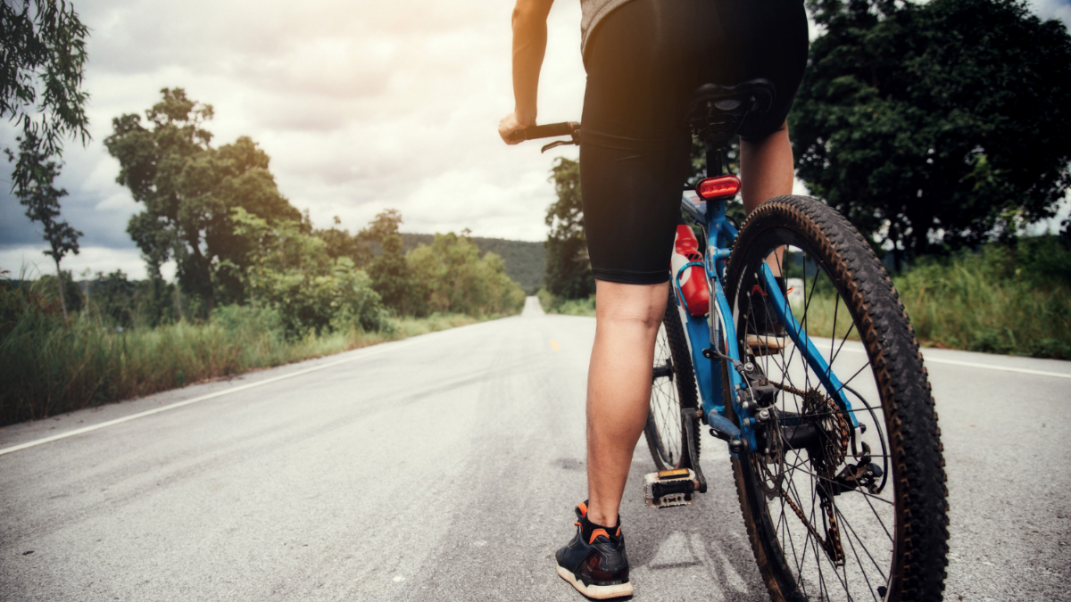 Un hombre subido a una bicicleta en una carretera mientras divisa el horizonte