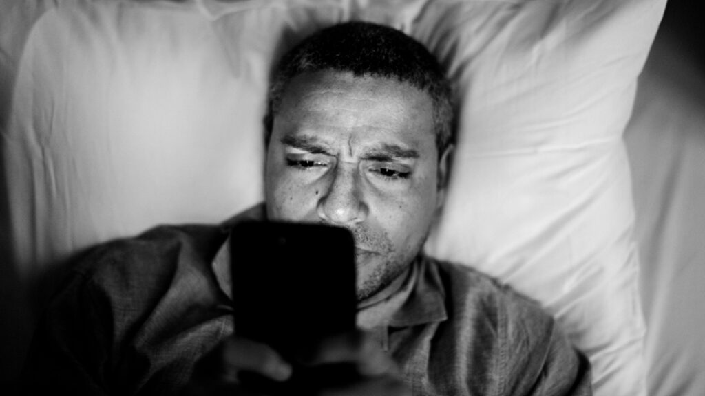 Un hombre maduro utiliza el teléfono mientras está en la cama
