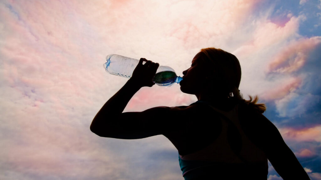 Una mujer bebe agua al atardecer