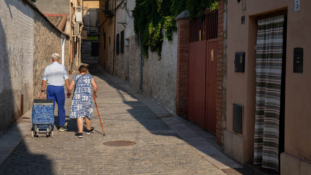 Una pareja de ancianos caminan de la mano por las calles de un pueblo