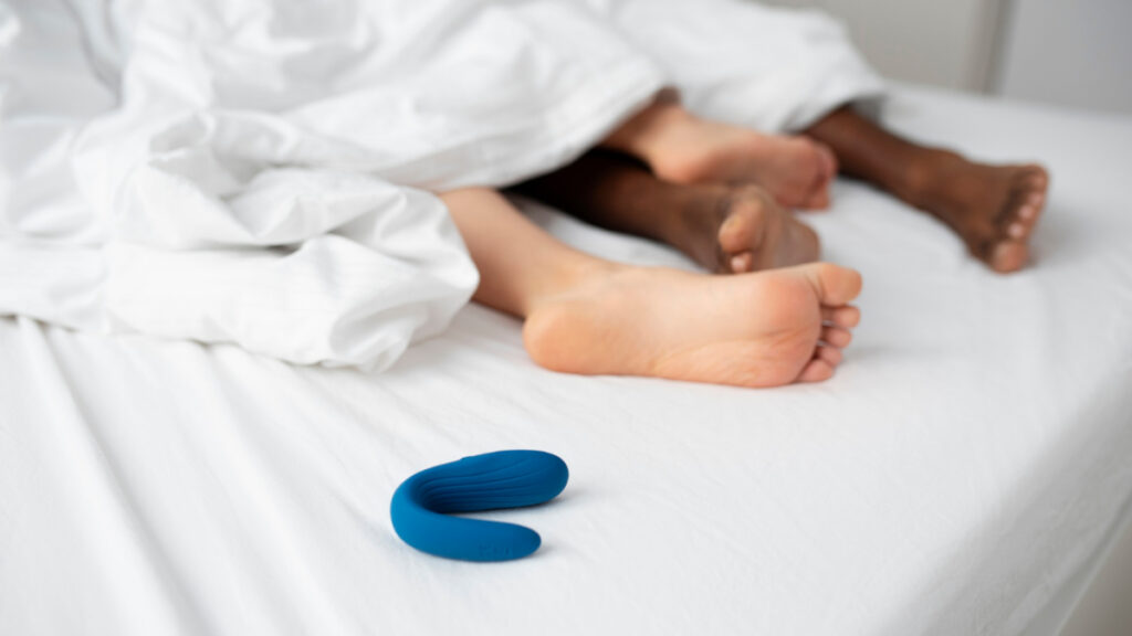 Una pareja permanece en la cama mientras un juguete sexual está sobre las sábanas.