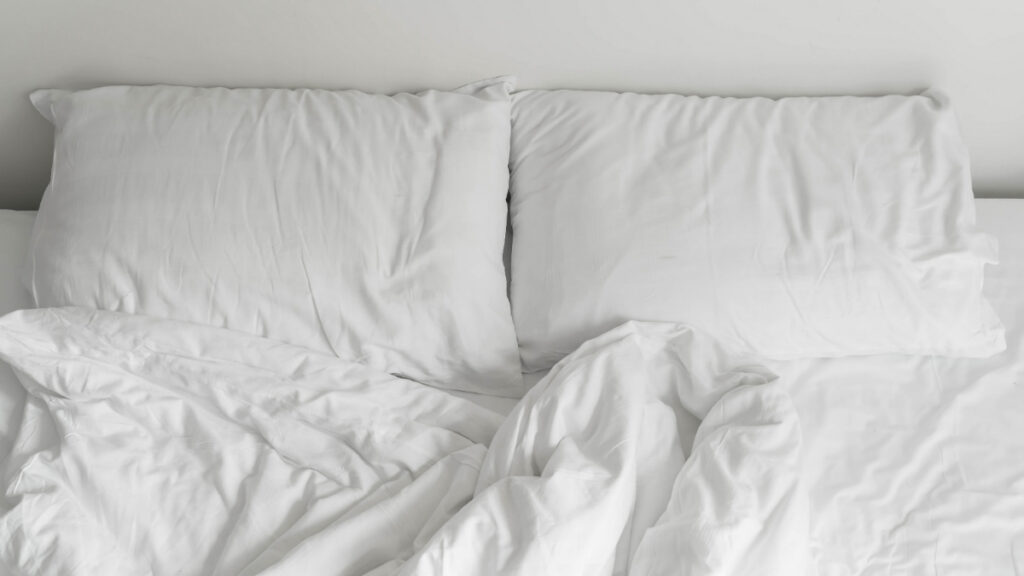 Dos almohadas en una cama deshecha.