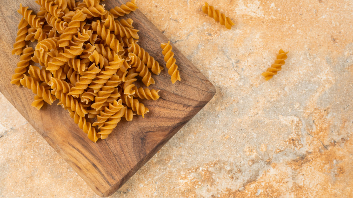 Una bandeja de madera con varios fusilli integrales sin cocinar