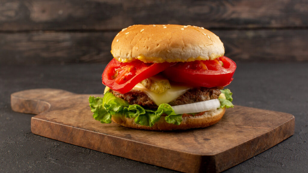 Una hamburguesa de pollo con queso y tomate.