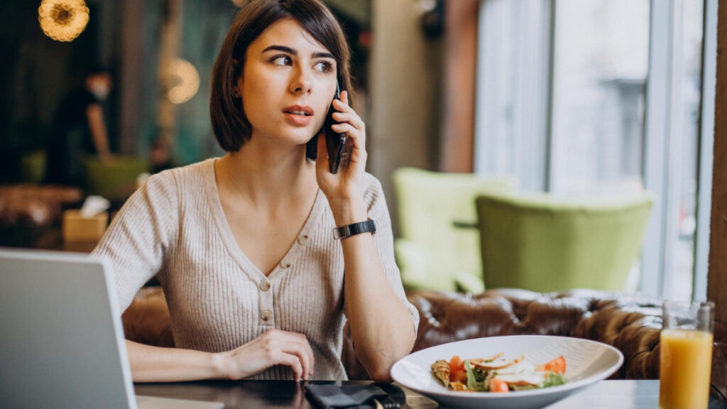Una mujer habla por teléfono mientras come