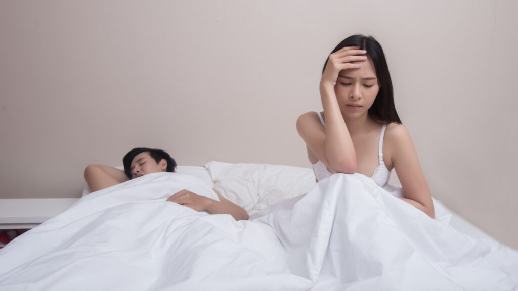 Una mujer se encuentra molesta en la cama mientras su pareja duerme, cansado por la adicción al porno