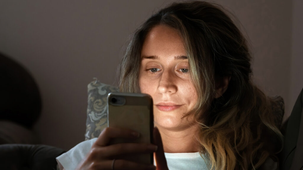 Una mujer se mantiene en vela mientras utiliza el teléfono móvil por la noche (vamping)