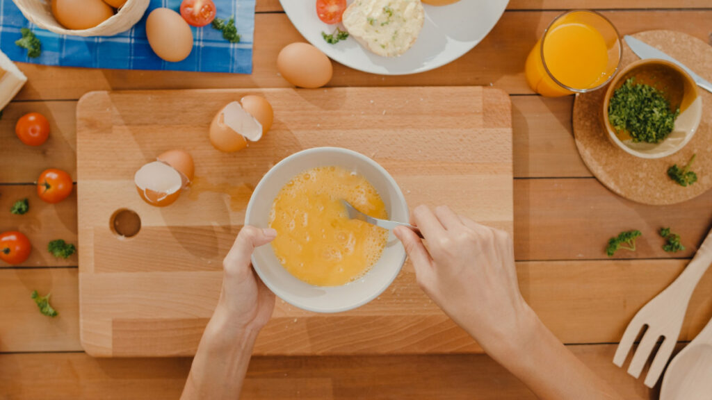 Unas manos batiendo huevos en un bol