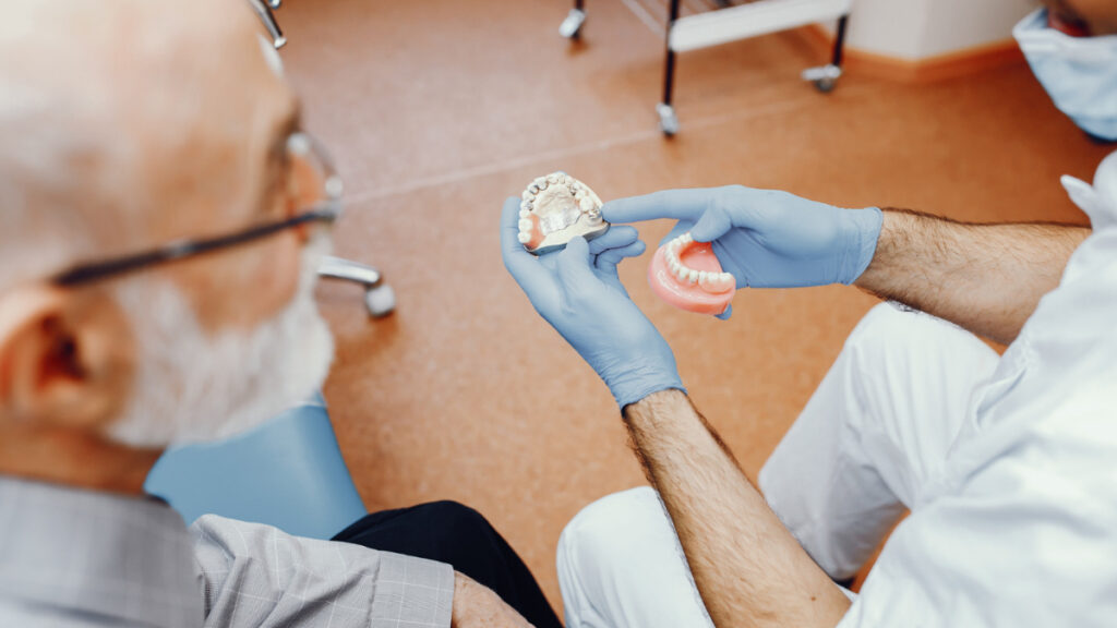 Un hombre mayor comprueba el molde de una dentadura postiza en el dentista.