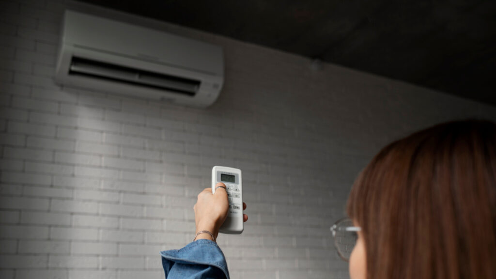 Una mujer controla la temperatura del aire acondicionado con un mando.