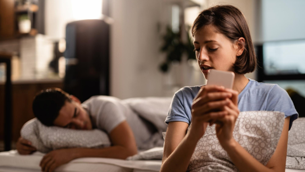 Una mujer mantiene una conversación telefónica mientras su pareja duerme
