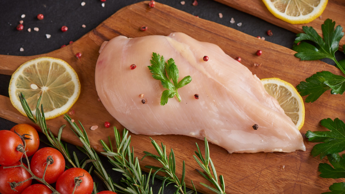 Una pechuga de pollo sobre una tabla de madera