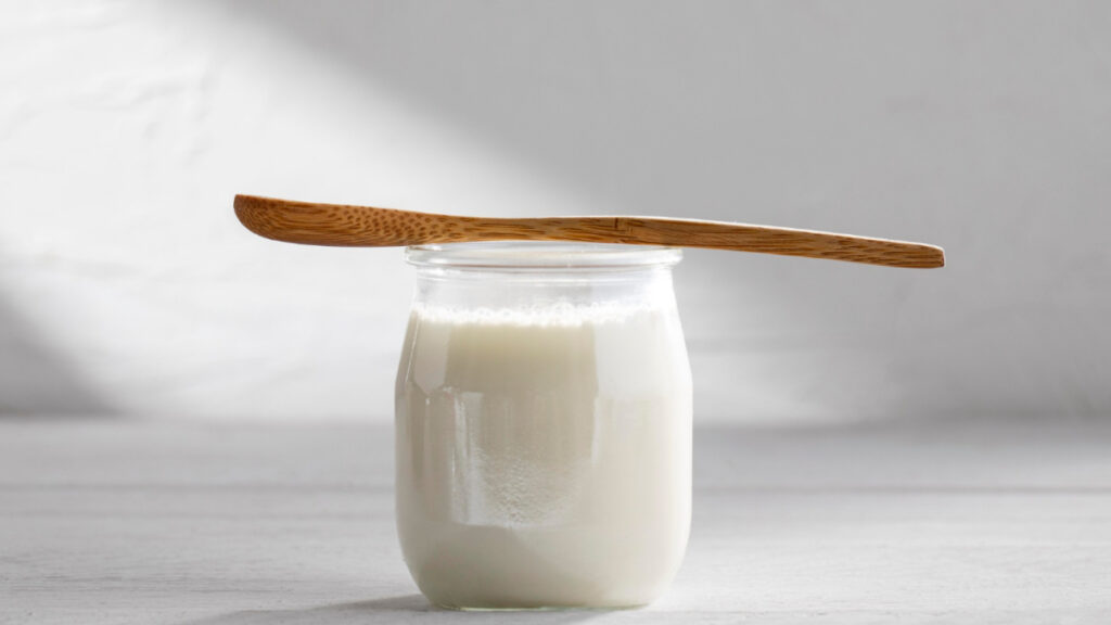 Yogur natural con una cuchara de madera.