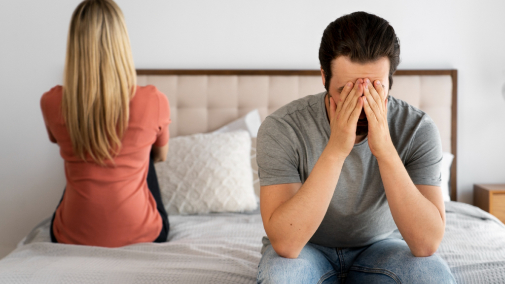 Un hombre con dolor de próstata en la cama con su mujer enfadada