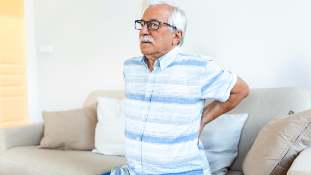 Un hombre mayor con dolor de espalda sentado en un sofá
