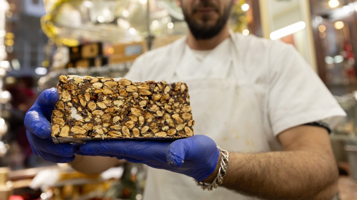 Un pastelero muestra un bloque de turrón en la tienda de turrones Casa Mira. 